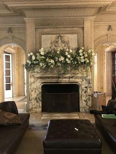 a living room filled with furniture and a fire place covered in flowers on top of a mantle