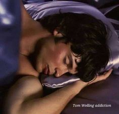 a young man sleeping in bed with his eyes closed and head resting on the pillow