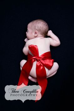 a baby wrapped in a red ribbon is laying on it's back with its hands behind his head