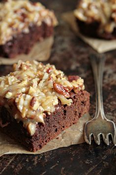 a piece of brownie with nuts on top is sitting on a piece of parchment paper