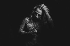 a man with long hair and tattoos holding his hands to his face in the water