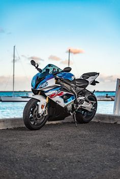 a blue and white motorcycle parked next to the water