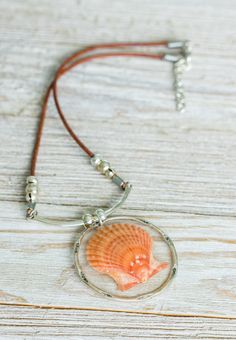 A real one of a kind Orange Scallop Shell Necklace. The shell is set in clear resin inside a silver hoop pendant. The pendant hangs from a silver bar attached to leather cording. The cording is approximately 15.5 inches long with 2 inches of additional chain to adjust the length. The shell was found by me and is from my personal shell collection. All of my shells are found along the SW Florida Gulf coast where I live. This is a real conversation piece! Scallop Shell Necklace, Gift For Step Mom, Real Conversation, Beach Lover Gifts, Shell Collection, Step Mom, Beaded Necklace Diy, Scallop Shell, Necklace Diy