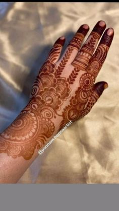 a hand with henna on it that is showing the intricate design and color scheme