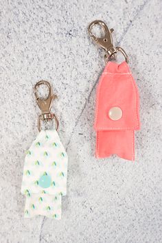 two keychains with different designs on them sitting next to each other in front of a stone surface