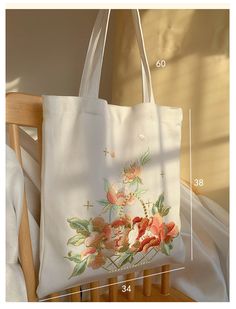 a white tote bag with pink flowers on it and measurements for the bottom half