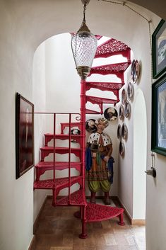 a red spiral staircase in a home with pictures on the wall