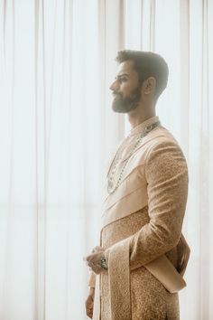 a man with a beard wearing a white and gold outfit