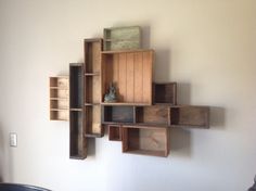 a wall mounted shelf with wooden boxes on it's sides and a vase in the middle