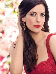 a beautiful woman in a red dress posing for a photo with flowers behind her head