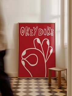 there is a red sign on the wall next to a small wooden table and chair