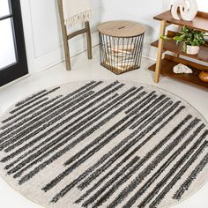 a round rug with black and white stripes on the floor next to a wooden shelf