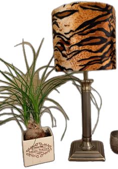 a lamp with a tiger print shade on it next to a potted grass plant