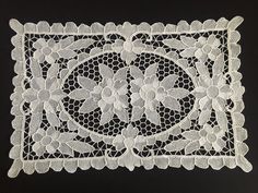 a white lace doily with flowers and leaves on black background, cut in half