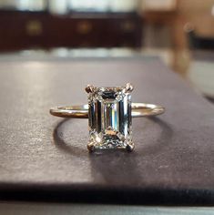 an emerald cut diamond ring sitting on top of a table