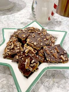 a plate full of chocolate and pecans on a marble counter top next to a glass of milk