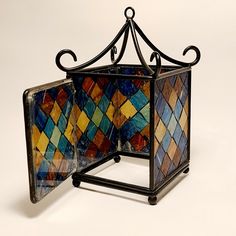 a multicolored stained glass box with wrought iron stand on white background, top view