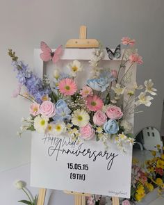 an easel with flowers on it and a sign that says happy anniversary to you