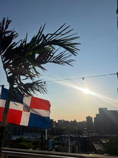 the sun shines brightly behind two flags in front of a large cityscape