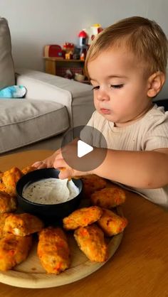 a little boy sitting at a table with some food in front of him