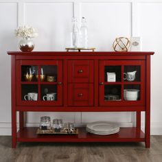 a red sideboard with glass doors and plates on it