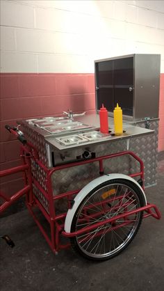 a red cart that has some food on top of it and drinks in the back