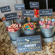 an assortment of candy in buckets with signs on them for graduation and sweet treats