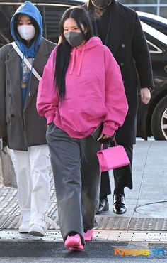 a woman wearing a face mask walks down the street with two other people behind her