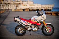 a red, white and blue motorcycle parked on the street