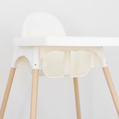 a white high chair with two wooden legs