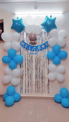 balloons and streamers decorate the entrance to a welcome home party with blue and white decorations