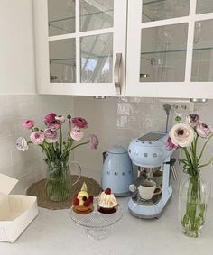 flowers in vases on the kitchen counter next to an ice cream maker and cupcake