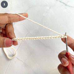 two hands are working on a piece of white string