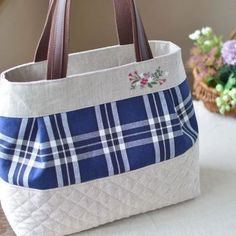 a blue and white bag sitting on top of a table next to a basket filled with flowers