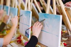 people are painting on easels with paintbrushes in front of the easel