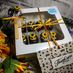 a box filled with chocolate covered donuts next to flowers