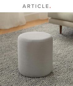 a white ottoman sitting on top of a gray rug next to a chair and table