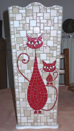 a mosaic vase with cats on it sitting on a table next to a lamp shade