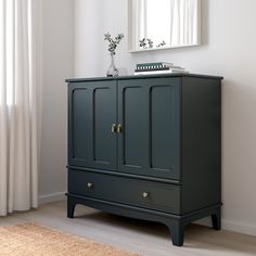 an armoire with two drawers and a mirror on the wall in a white room