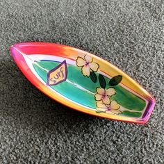 a colorful surfboard sitting on top of a carpeted floor with flowers painted on it