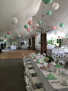 tables and chairs are set up in a tent with paper lanterns hanging from the ceiling