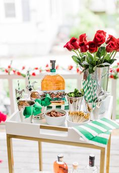 a table with flowers and drinks on it, including roses in vases next to the bar cart