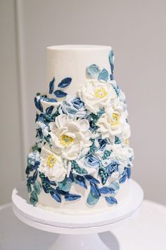 a white and blue wedding cake with flowers on it