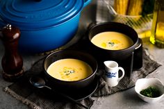 two bowls filled with soup sitting on top of a table next to a blue pot