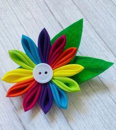 A beautifully handmade fabric rainbow flower brooch pin.  Created using the kanzashi method using cotton fabrics finished with a button centre and felt leaves.  Each flower is around 2.5 inches accross with an added inch for the leaves.  If buying as a gift it can be sent directly to the recipient. Please ensure the delivery address is correct when you place the order. You can also add a gift message so the recipient can see who sent the gift.  This listing is for a rainbow brooch pin.  Other co Handmade Multicolor Flower Brooches, Flower Brooch Handmade, Rainbow Gifts, Fabric Flower Pins, Rainbow Pin, Felt Leaves, Brooch Handmade, Women Flower, Rainbow Gift