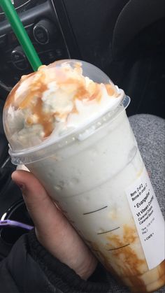 a person holding a drink in their hand while sitting in the backseat of a car