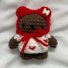 a crocheted teddy bear wearing a white and red dress with a bow on it's head