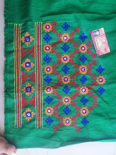 a green cloth with colorful flowers on it and a small book laying next to it