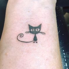 a small black cat tattoo on the wrist