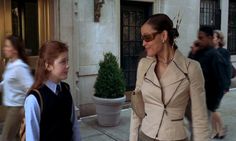 two women walking down the street in front of a building, one is talking to another woman